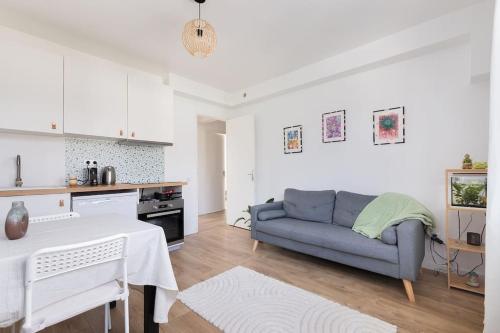 un salon avec un canapé bleu et une table dans l'établissement Appartement Paris CDG Parc Expo Stade, à Aulnay-sous-Bois