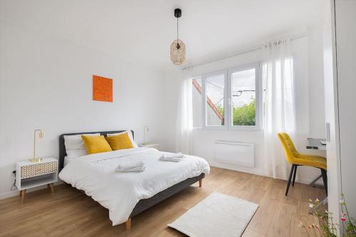 a white bedroom with a bed and a yellow chair at Appartement Paris CDG Parc Expo Stade in Aulnay-sous-Bois