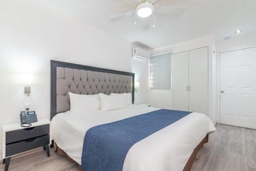 a bedroom with a large white bed with a blue blanket at European Life Style Executive Suites in Guadalajara