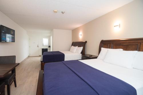a hotel room with two beds and a desk at Diplomat Inn in Niagara Falls