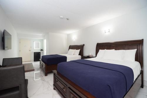 a hotel room with two beds and a television at Diplomat Inn in Niagara Falls
