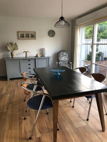 une salle à manger avec une table et des chaises noires dans l'établissement Maison de caractère au village, à Pontenx-les-Forges