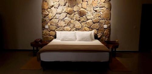 een bed in een kamer met een stenen muur bij Casa 422 - Loft Jasmim in Santana do Riacho
