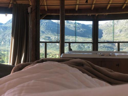 een slaapkamer met uitzicht op een badkuip en de bergen bij Casa 422 - Loft Jasmim in Santana do Riacho