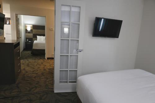 a bedroom with a bed and a television on the wall at MainStay Suites Madison Airport in Madison