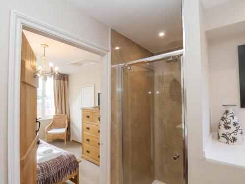 a bathroom with a shower and a bedroom at Rooftops Cottage in Whitby