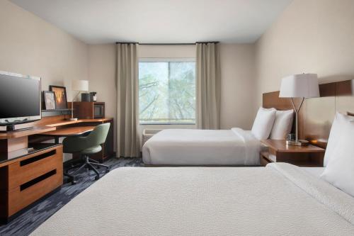 a hotel room with two beds and a desk and a television at Fairfield Inn & Suites by Marriott Watertown Thousand Islands in Watertown