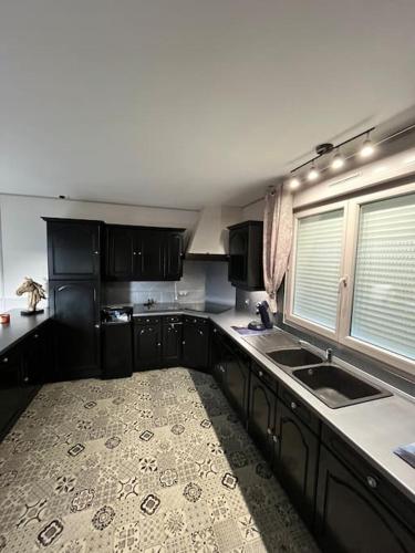 a kitchen with black cabinets and a sink at Gîte de Beaufresne in Haudricourt