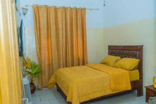 a bedroom with a bed with yellow sheets and a curtain at AFRIEUROTEXT Kamerun-High Standing-Appartements-Wifi-Security-Restaurant-modern Kitchen in Yaoundé