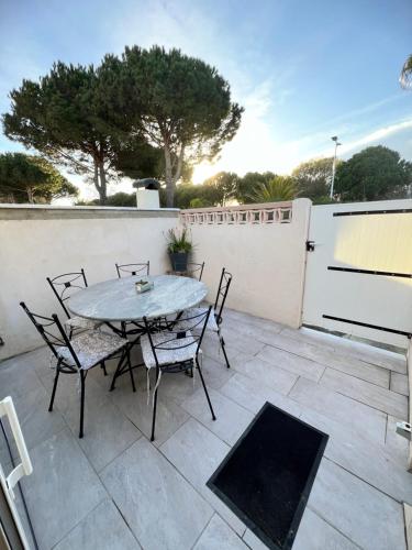 un patio avec une table et des chaises et une clôture dans l'établissement Villa cosy bleue, à Gruissan