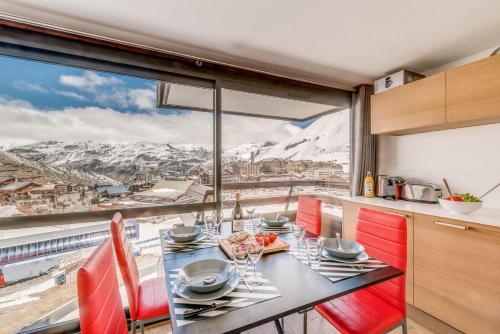 une cuisine avec une table et des chaises rouges ainsi qu'une grande fenêtre dans l'établissement Résidence Palafour - Studio cabine 4 personnes pieds des pistes - balcon vue Grande Sassière MAE-3629, à Tignes