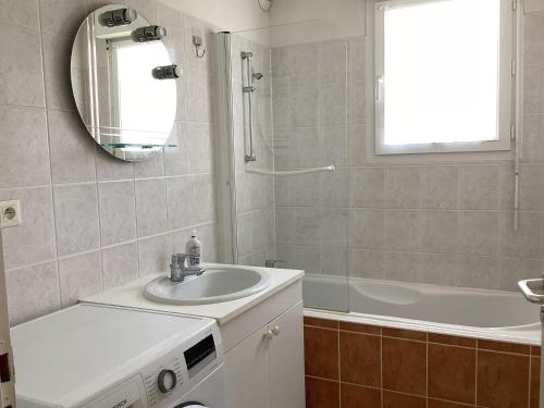 une salle de bain avec un lavabo, une baignoire et un miroir dans l'établissement Type 2 rue Alsace lorraine 10mn plage, à La Rochelle