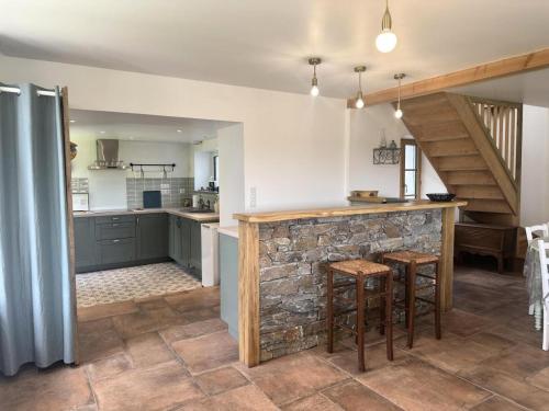 a kitchen with a stone wall and a counter with stools at Gîte de France Gîte bel air 3 épis - Gîte de France 6 personnes MAE-0124 in Saint-Étienne-aux-Clos