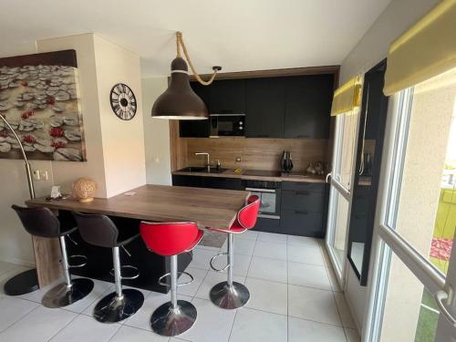 une cuisine avec une table en bois et des chaises rouges dans l'établissement Spacieux appt familial - 3 chb - Parking - Wifi, à Arcachon