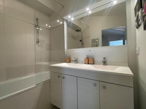 une salle de bain blanche avec un lavabo et une douche dans l'établissement Spacieux appt familial - 3 chb - Parking - Wifi, à Arcachon