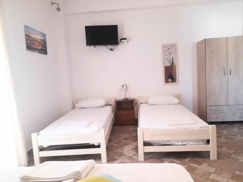 two beds in a room with a tv on the wall at A Lodge in Tinos Town
