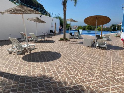 een patio met stoelen en parasols naast een zwembad bij Apparemment Noura in Tetouan