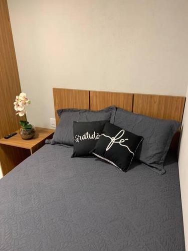 a bed with black pillows and a wooden headboard at Microcasa na cobertura in Santa Teresa