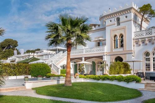 a large white mansion with a palm tree in the yard at La Villa Mauresque in Saint-Rapha&euml;l