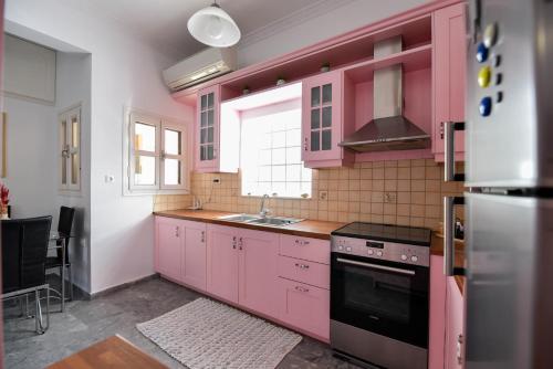 a pink kitchen with a sink and a stove at Coo-Coo Place in Kalamata