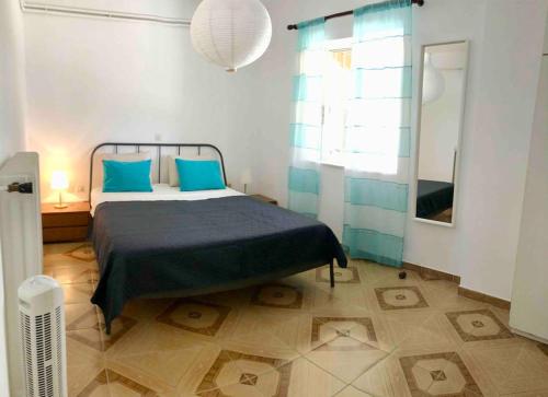 a bedroom with a bed with blue pillows and a window at Fysis Panorama spectacular view in Porto Rafti
