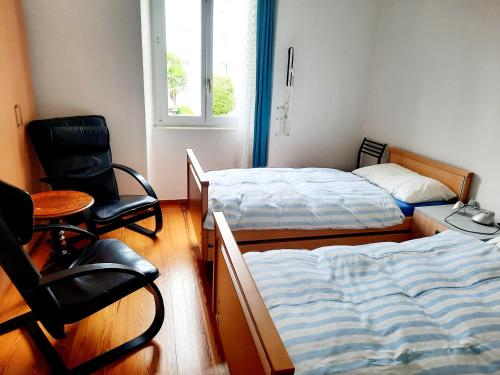 a bedroom with two beds and a desk and a chair at Ampie camere Locarno in Locarno