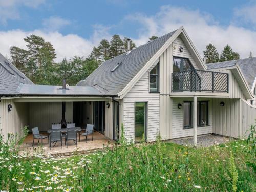 a house with a patio with a table and chairs at Golden Eagle Lodge in Kingussie