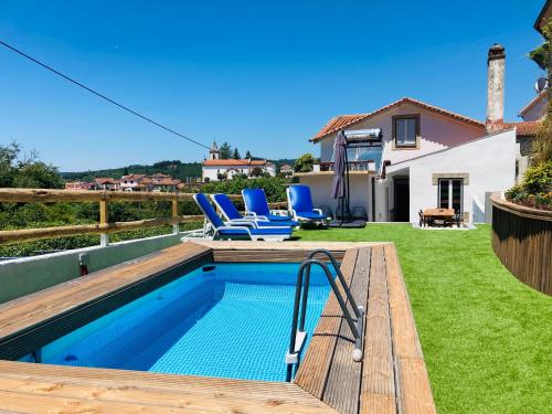 a backyard with a swimming pool and a deck with blue chairs at Casa SuasDuas in Vila Cova de Alva
