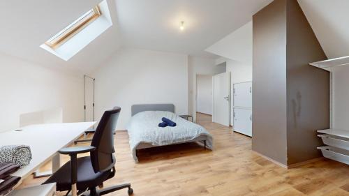 une chambre blanche avec un bureau et un lit dans l'établissement Le nid perché Mulhouse, à Mulhouse