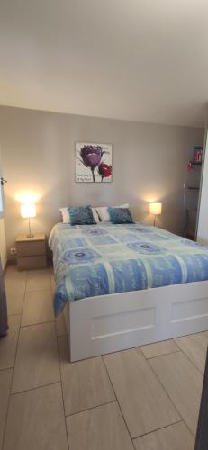 - une chambre avec un lit avec une couette bleue et 2 lampes dans l'établissement Chez LINAT - Paisible appartement avec jardin et vue mer, à Vallauris