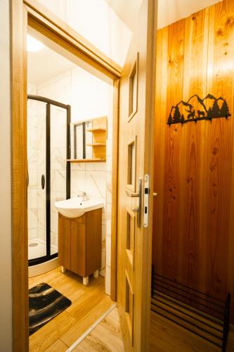 a bathroom with a sink and a mirror and a door at Leśniczówka w Dolinie in Świeradów-Zdrój