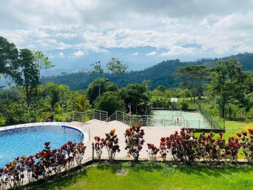 a swimming pool with flowers and a tennis court at Finca La Vistosa in Sasaima