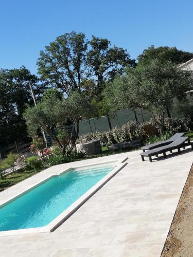 une piscine avec un banc et des arbres en arrière-plan dans l'établissement Sophie et Jamiel, à Eyragues