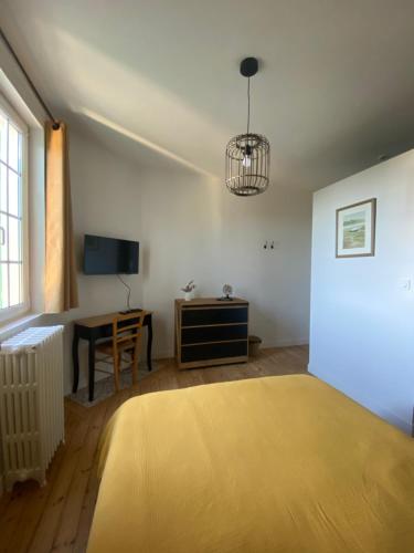 a bedroom with a bed and a desk and a television at La Hacienda Verde in Saint-Jouan-des-Guérets