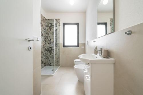 a white bathroom with a toilet and a sink at Holiday Camelia in Pirri