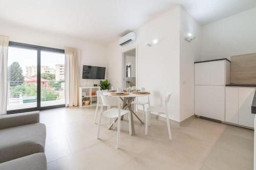 a white kitchen and living room with a table and chairs at Holiday Camelia in Pirri