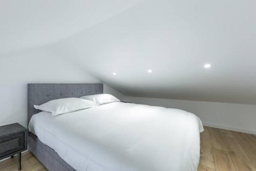 a bedroom with a white bed and a night stand at Luxueux et unique - Bobigny - Paris in Bobigny