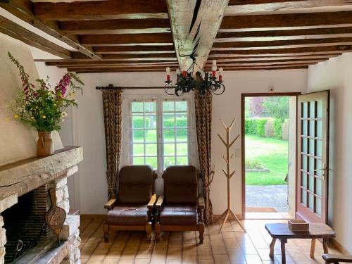 un salon avec deux chaises et une cheminée dans l'établissement Maison normande avec grand jardin proche de la mer et de Paris, à Beaumont-le-Roger