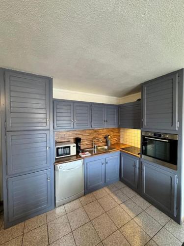 une cuisine avec des armoires bleues et un évier dans l'établissement Cœur du Village - 4 Pers - Clim, à Gruissan