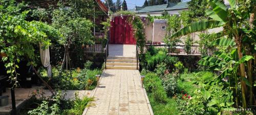 a garden with a brick walkway leading to a red door at Kuki dom Ganja in Bagbanlar