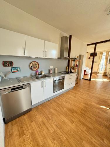 une cuisine avec des armoires blanches et des appareils en acier inoxydable dans l'établissement Le Stanislas Confort à Colmar - centre ville -, à Colmar