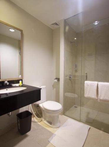 a bathroom with a shower and a toilet and a sink at Genio Hotel Manado in Manado