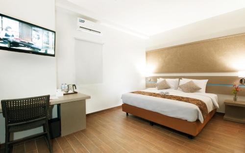 a hotel room with a bed and a desk at Genio Hotel Manado in Manado