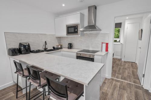 a white kitchen with a counter and a kitchen island at Cosy & Comfortable 2BR in Oban - Walk to Waterfront in Oban