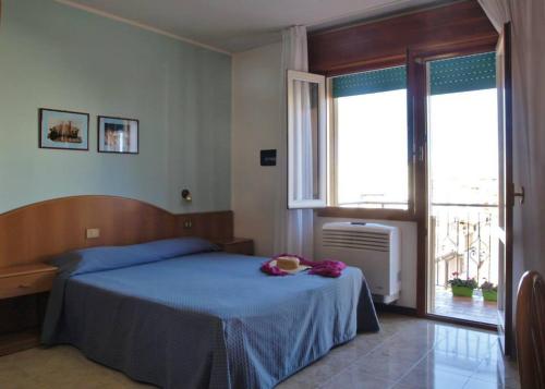 a bedroom with a blue bed and a window at Hotel Fornaro in Caorle