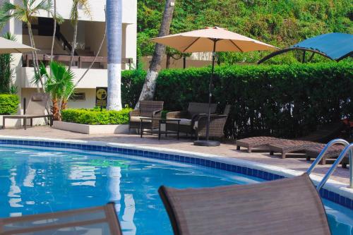 a swimming pool with chairs and an umbrella at El Dorado in Los Mochis