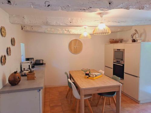 a kitchen with a wooden table with chairs and a table and a kitchen with at Gîte Chaumière de Floranges 6 personnes Morbihan in La Chapelle-Neuve