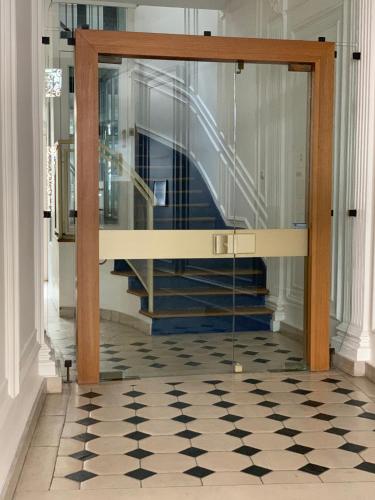 un couloir avec une porte en verre menant à un escalier dans l'établissement Chaleureux 3 pièces haussmanien au cœur du Quartier Latin, à Paris