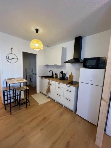une cuisine avec un réfrigérateur blanc et une table dans l'établissement Studio Le petit Larros, à Gujan-Mestras