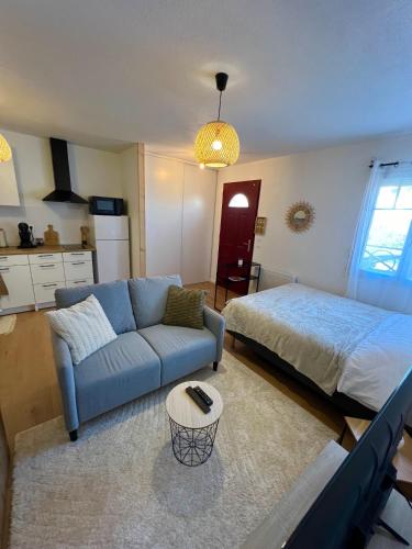 - un salon avec un canapé bleu et un lit dans l'établissement Studio Le petit Larros, à Gujan-Mestras